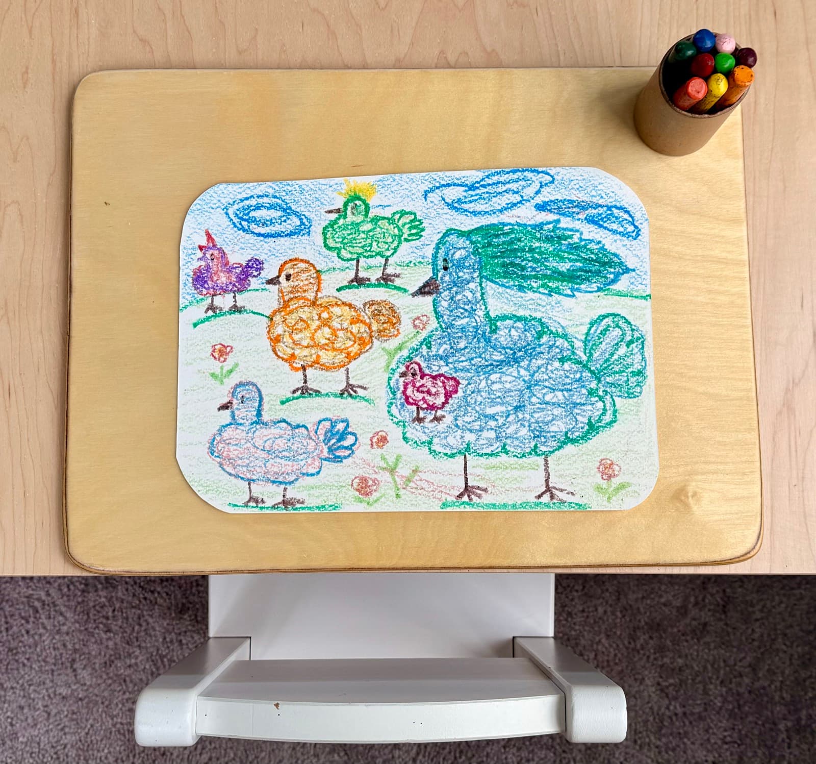 A child's colorful crayon drawing of birds and chickens made in class