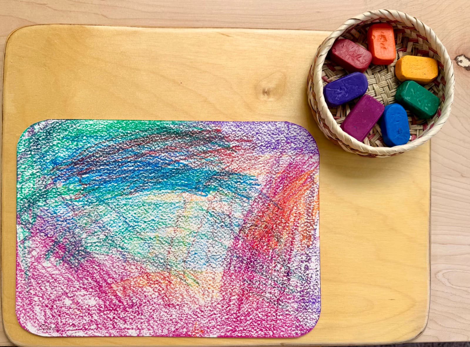 A finished crayon drawing with a basket of beeswax crayons